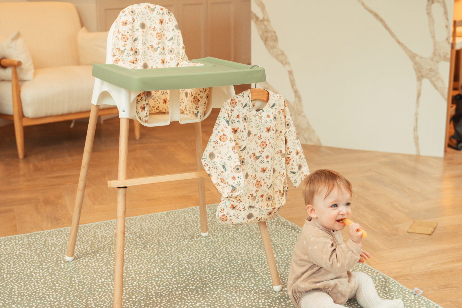 Baby seated in IKEA Antilop highchair with sage silicone placemat, wipe-clean cushion and natural oak leg wrpas by AZEbabydream