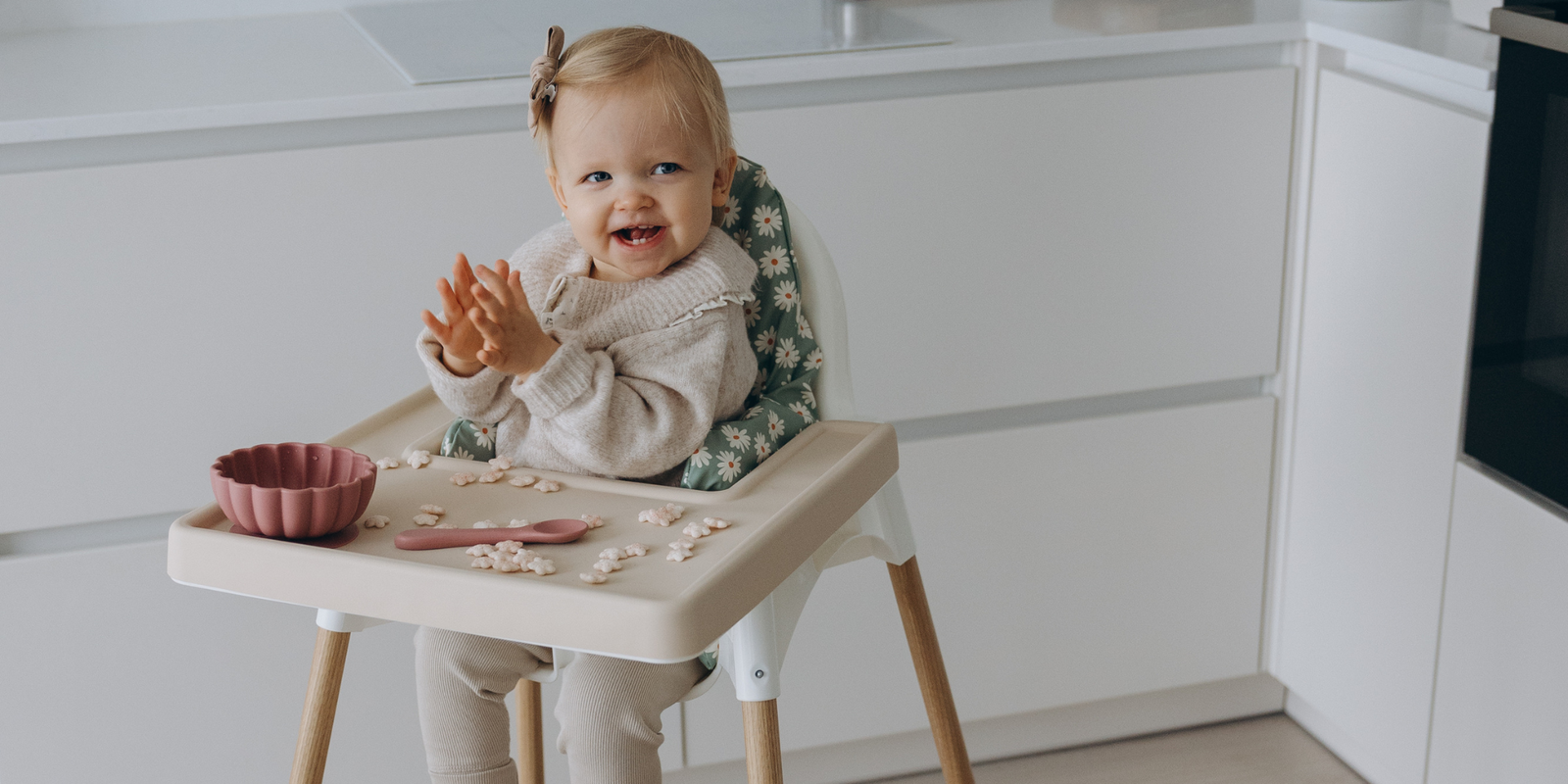 Baby seated in IKEA Antilop highchair with cream silicone placemat, wipe-clean cushion and natural oak leg wrpas by AZEbabydream