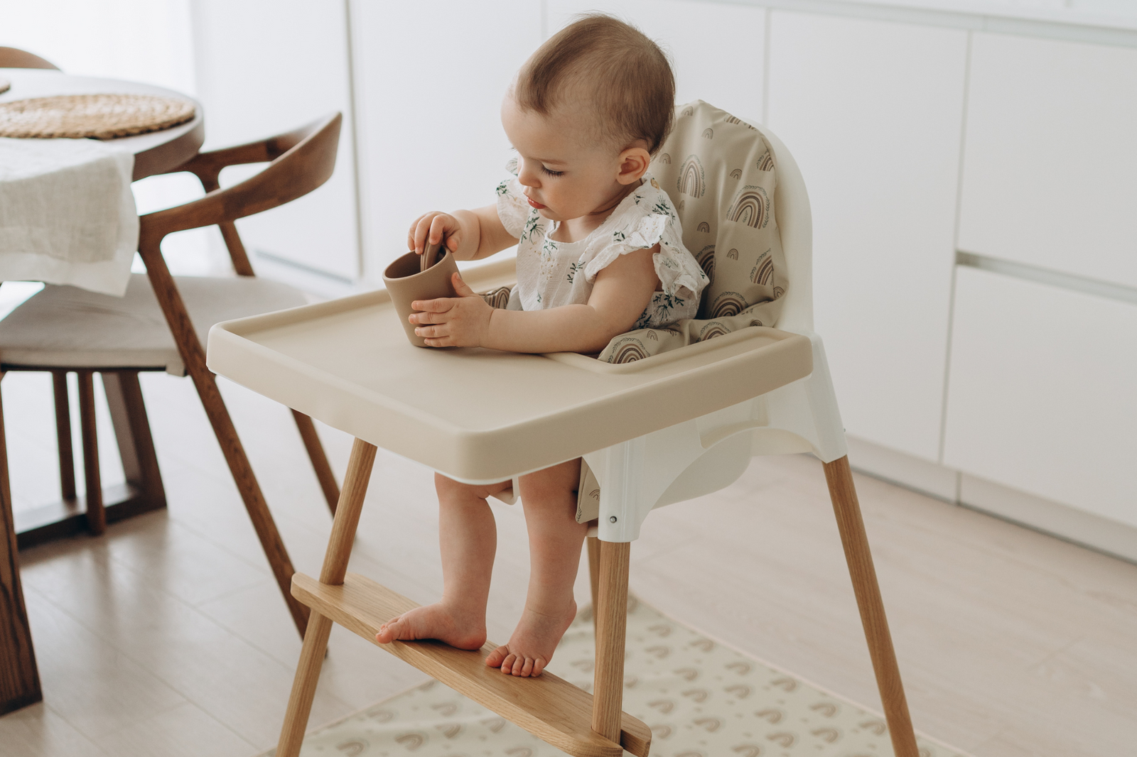 Baby seated in IKEA Antilop highchair with cream silicone placemat, wipe-clean cushion and natural oak leg wrpas by AZEbabydream