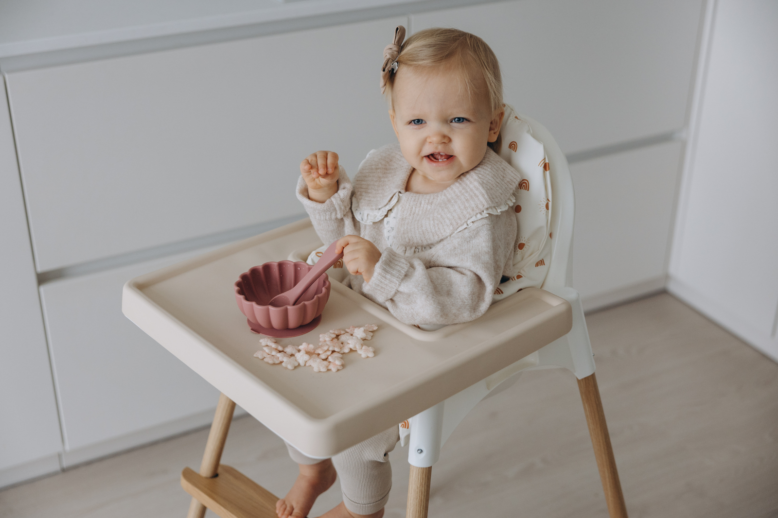 Baby seated in IKEA Antilop highchair with cream silicone placemat, wipe-clean cushion and natural oak leg wrpas by AZEbabydream