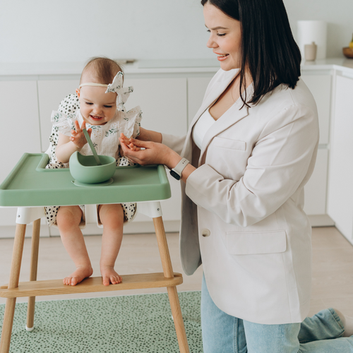 mum feeding baby in IKEA Antilop highchair with AZEbabydream green silicone placemat, matching suction bowl and weaning spoon